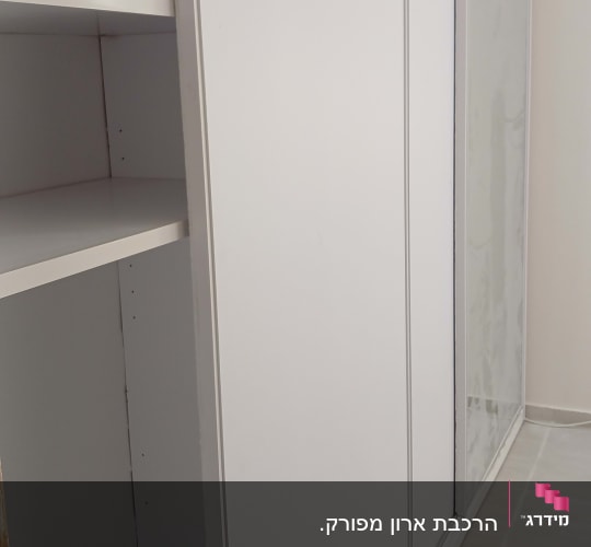 ארון הזזה לבן וגדול עם מדפים פנימיים שהורכב בחדר